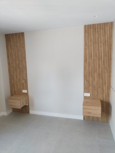 Pared vacía con revestimiento de madera y dos estantes en los extremos.