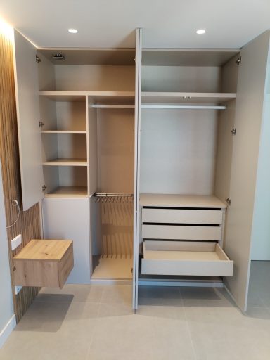 Armario moderno con estantes, barra para colgar ropa y cajones en un espacio minimalista.