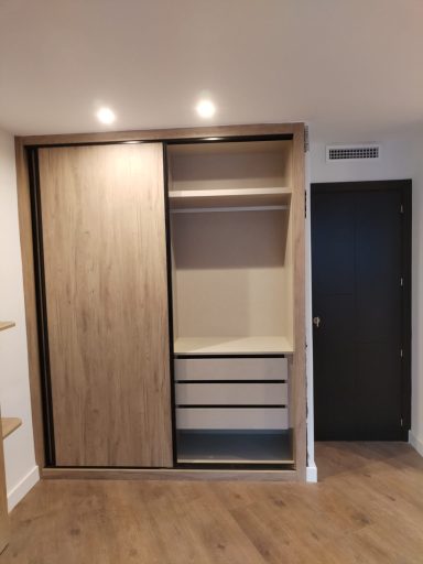 Armario empotrado de madera con puertas correderas y cajones en la parte inferior.