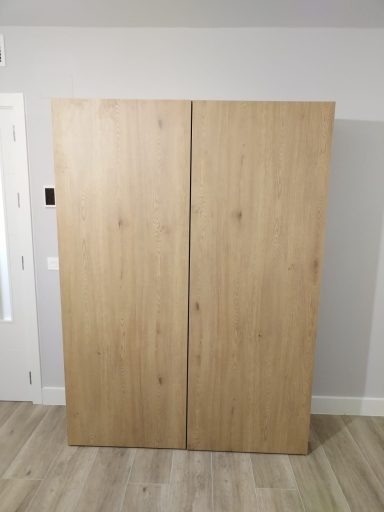 Armario de dos puertas de madera clara, con un diseño simple y moderno.