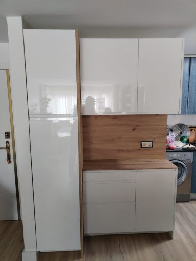 Cocina moderna con armarios blancos y detalles de madera, refrigerador incluido.