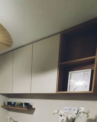Estantería de madera con compartimento abierto y cuadros decorativos sobre una pared.