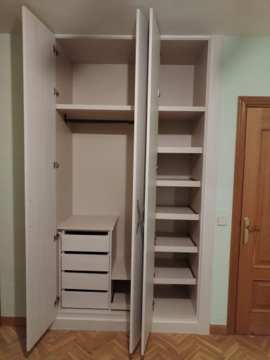 Armario empotrado con puertas, estantes y cajones en su interior.