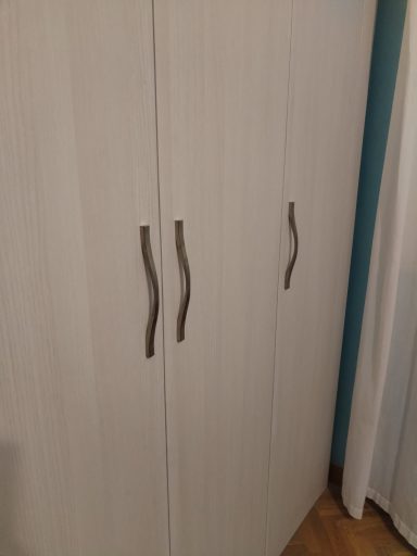 Armario de madera clara con puertas y tiradores en forma de curvatura.