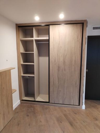Armario empotrado con puertas correderas y estantes interiores de madera clara.