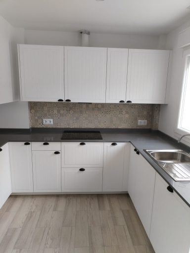 Cocina moderna con muebles blancos, encimera gris y backsplash de azulejos.