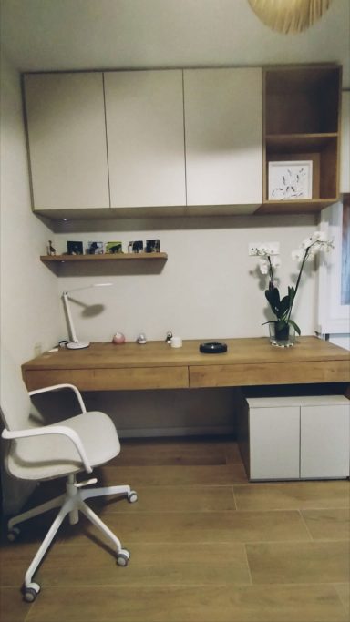 Escritorio moderno de madera con silla blanca y decoración minimalista en un ambiente acogedor.