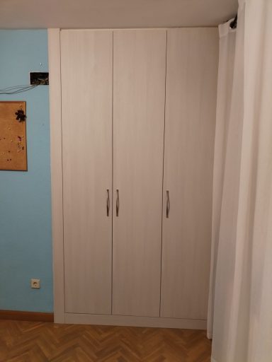 Armario de puertas blancas en una pared de color azul claro.