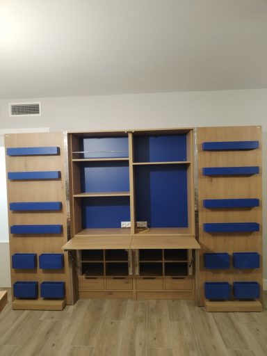 Mueble de pared con estantes y paneles azules sobre fondo de madera clara.