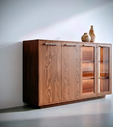 Mueble de madera oscura con puertas y cajones, decorado con jarras en la parte superior.