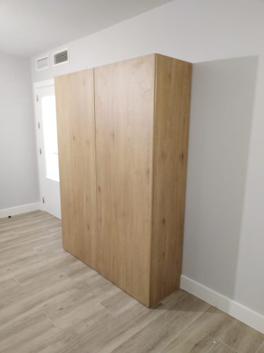 Armario de madera claro con puertas abatibles en una habitación minimalista.